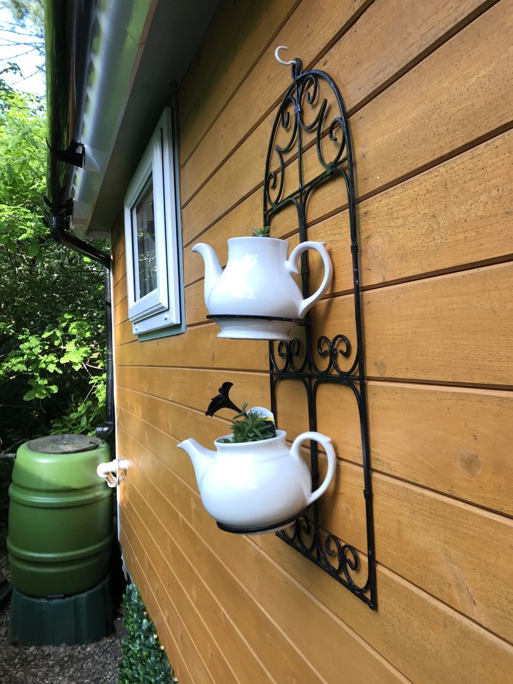 Teapots on an iron rack on the wooden wall